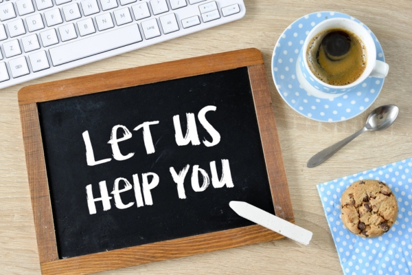 Let Us Help You written on a chalkboard beside a coffee cup and a cookie