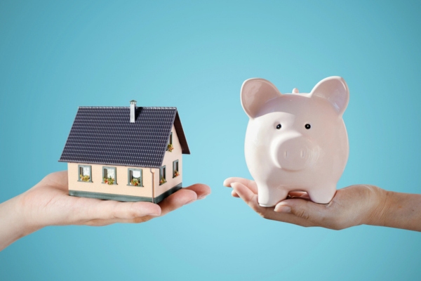 hands holding a miniature house and a piggy bank depicting Cost Savings for Homeowners