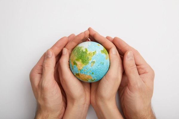 man and woman join hands holding an Earth model depicting Environmental Advantages of High-Efficiency Heating Systems