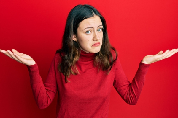 woman wearing a red turtleneck top shrugging depicting How Modern High-Efficiency Heating Systems Operate