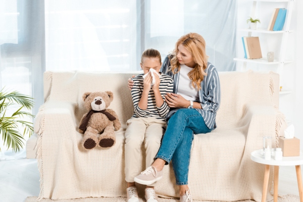 Mom aiding to sneezing kid depicting HVAC allergies