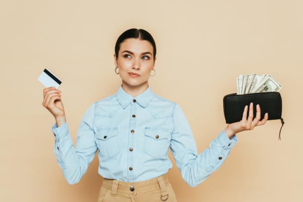 woman holding card and wallet with cash on each hand evaluating propane delivery expenses