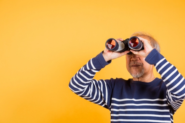 Asian man looking through binoculars depicting what to look for in an HVAC contractor