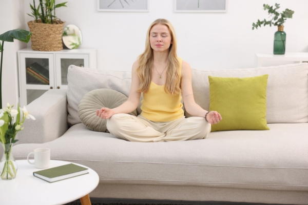 woman meditating at home on the couch depicting improved indoor air quality