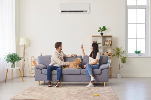 couple with a dog turning on ductless HVAC while lounging on the couch