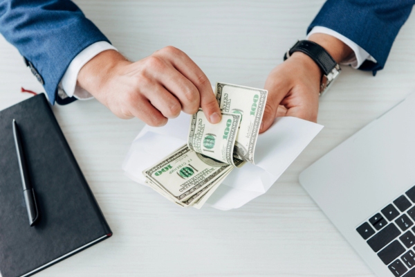 Cropped view of man holding envelope with dollar banknotes depicting Average Cost to Install a System 2000 Boiler