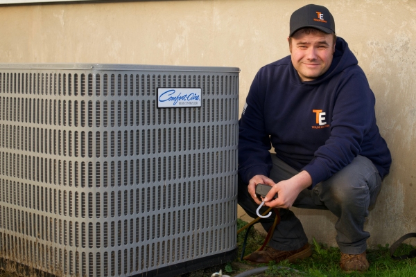 Taylor Energy HVAC technician beside an air conditioner outdoor unit