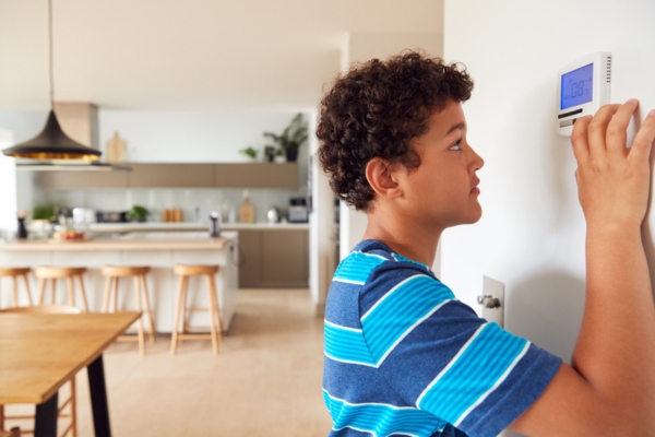 kid adjusting home thermostat