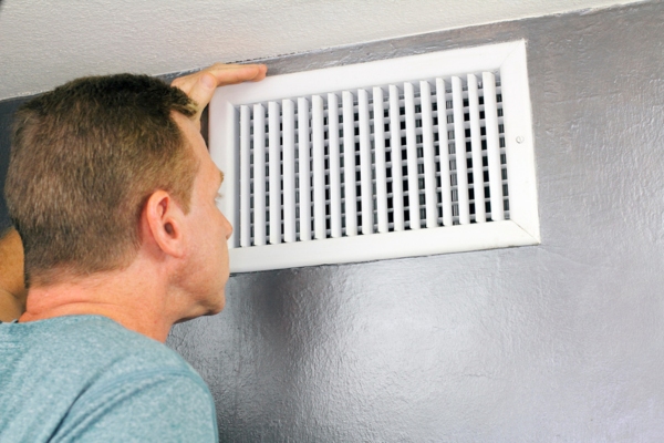 homeowner checking HVAC vent for weak airflow