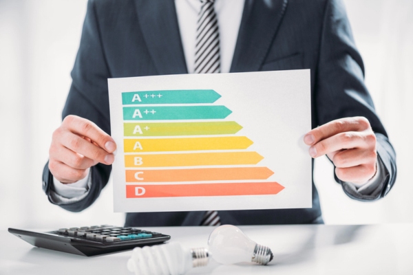 Cropped view of man in suit holding a paper with efficiency rating chart depicting AFUE vs AFUE2