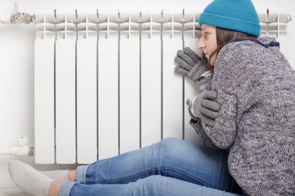 woman feeling cold sitting by the oil radiator due to heating system failure