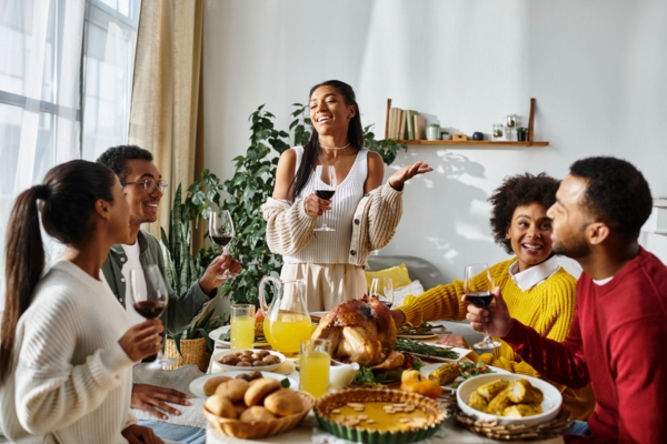 homeowner standing with guests sitting down during thanksgiving dinner party