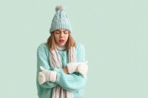 woman feeling cold indoors wearing full winter clothes due to malfunctioning furnace