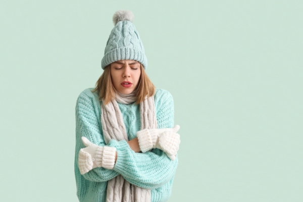 woman feeling cold indoors wearing full winter clothes due to malfunctioning furnace