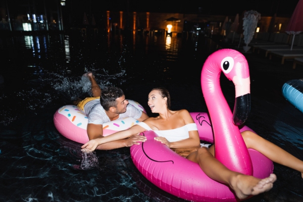 couple enjoying heated pool at night with floaters