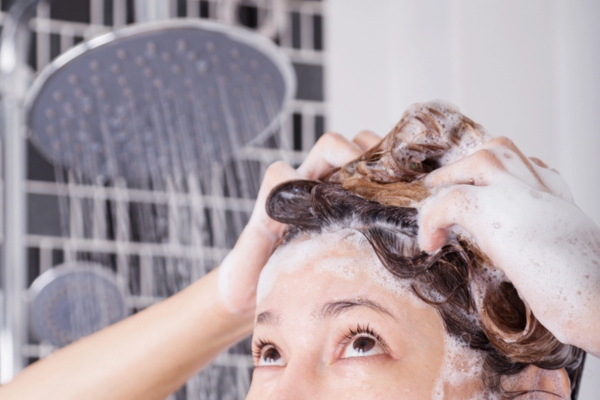cropped view of a woman showering when water suddenly becomes cold