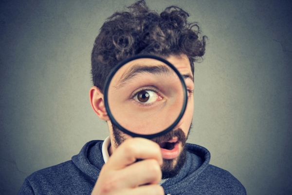 man looking through a magnifying glass depicting Heating Oil Tank Gauge Reading