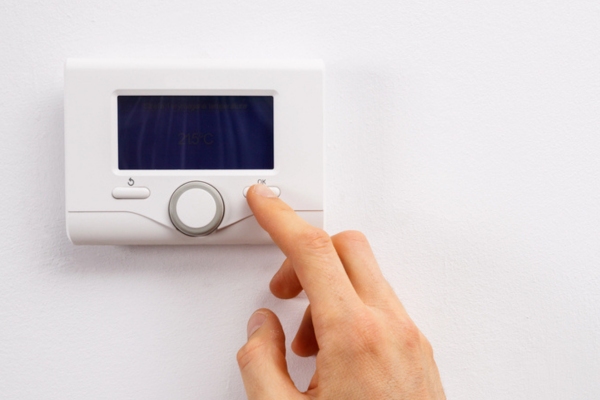 homeowner checking a malfunctioning thermostat
