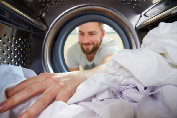 man reaching for dried clothes inside a propane-powered dryer