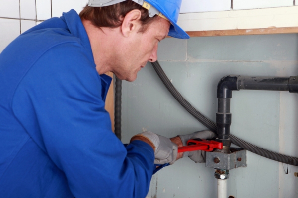 Plumber inspecting and tightening a joint with a wrench
