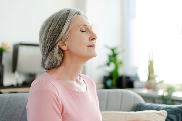 image of a woman with her eyes closed breathing in indoor air