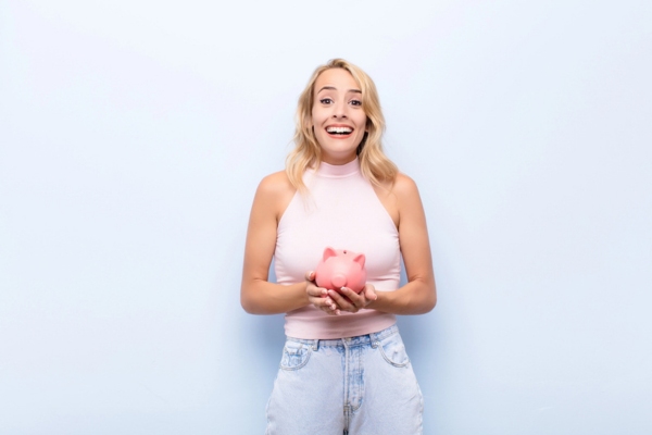woman feeling happy while holding a piggy bank depicting Reduced Energy Expenses