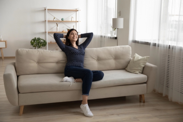 woman feeling happy while lounging on the couch depicting Variable-Speed Functionality and Responsive System Performance