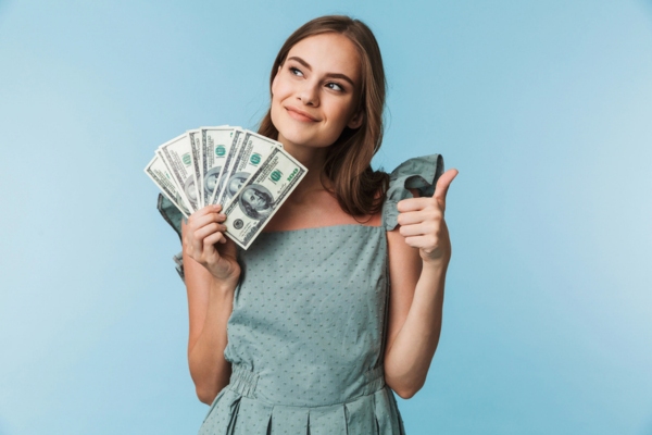 woman holding dollar bills on one hand and doing a thumbs up on the other depicting Time Efficiency and Financial Advantages of Heating Oil Delivery