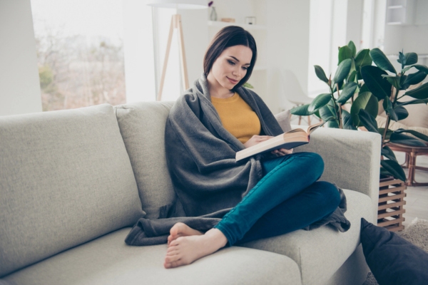 woman wrapped in blanket while lounging on a couch depicting Winter-Prepared Protection