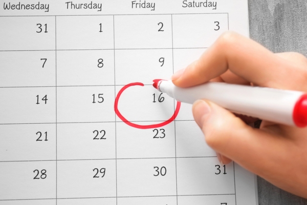 Female hand encircling date in calendar depicting Service Scheduling
