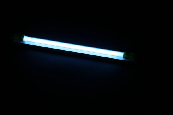 Modern ultraviolet lamp glowing on black background