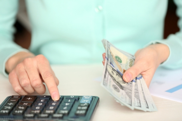 Woman counting money and working on calculator