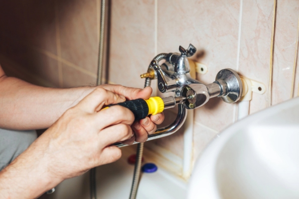 plumber fixing a leaky faucet in the bathroom