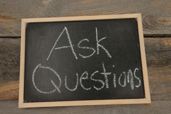 Ask Questions written on a chalkboard depicting Air Conditioning Scams FAQs