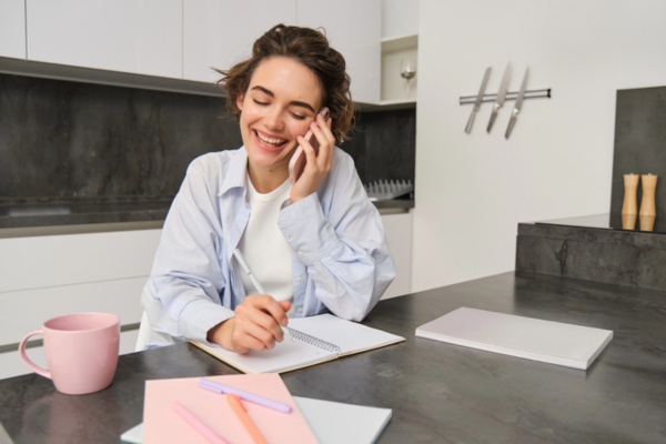 woman talking with someone on the phone while writing on a notebook depicting Schedule Professional Plumbing Service