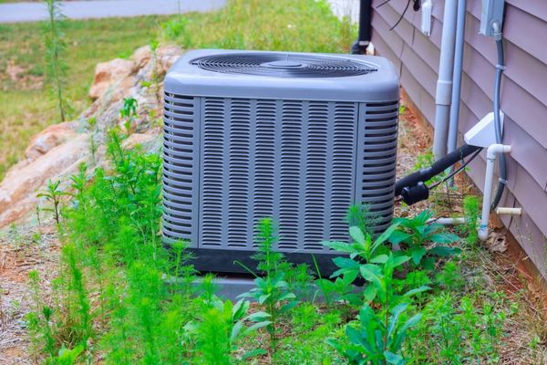 air conditioner unit installed outside the house with plants nearby