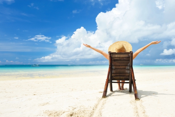 girl with hat sitting on a chair by the beach