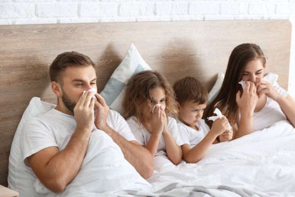 family feeling sick and blowing nose on tissue while in the bedroom