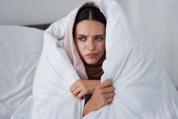 woman covered in thick blankets at home due to Failing Furnace Ignitor